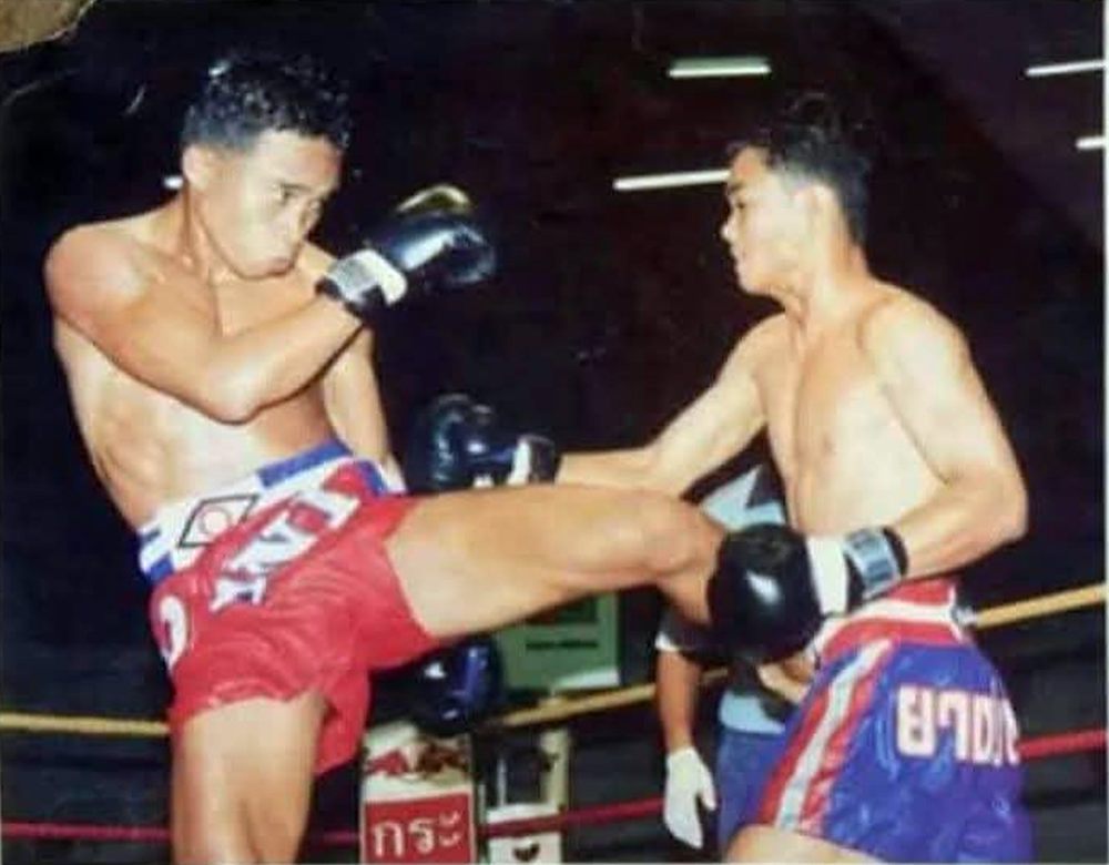 Two fighters exchanging kicks in a Thai stadium ring, from Kru Youn's fighting days